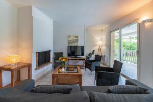 een woonkamer met een bank, stoelen en een tv bij Lagrange Vacances - Eden Parc Golf in Lacanau-Océan