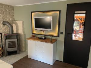 OderbergにあるFerienhaus Garten und Pool Ferienwohnung und Gästehausのストーブのあるリビングルームのスタンドに置かれたテレビ