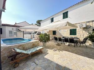 a pool with chairs and umbrellas next to a building at La Familia in Šibenik