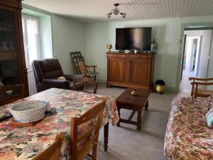 ein Wohnzimmer mit Tisch und Fernseher in der Unterkunft Maison de Famille à Soulier in Gramat
