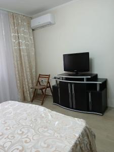 een slaapkamer met een bed en een tv op een standaard bij Vila cu Flori in Eforie Sud