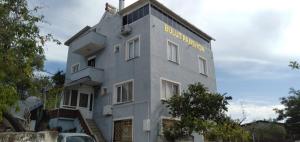 a white building with a sign on the side of it at GEYİKLİ BULUT Pansiyon in Ezine