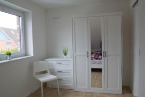a white closet with a chair in a room at 6 Personen Ferienhaus mit Sauna, Whirlpool, zwei Duschen sowie Kaminofen in Otterndorf in Otterndorf