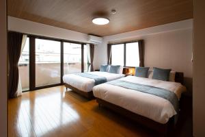 a bedroom with two beds and a large window at エレガンス表町-市内中心部でアクセス良好 ワンフロア貸し切りでパーティもOｋ駐車料金無料 in Okayama
