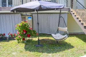 a swing in front of a house with an umbrella at Mitro Apartments Sun & Sea, Vrasna beach in Nea Vrasna +65 photos