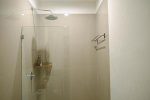 a shower with a glass door in a bathroom at MIMOYA Guest House, Sanur in Sanur