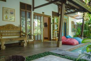 a living room with a bench and a pool at MIMOYA Guest House, Sanur in Sanur
