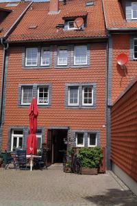 ein rotes Gebäude mit einem Regenschirm, einem Tisch und Stühlen in der Unterkunft Ratsstübchen in Wernigerode