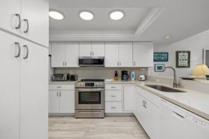 a kitchen with white cabinets and stainless steel appliances at Edgewater Condo Unit #303 Apts in South Padre Island