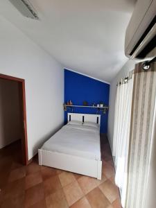 a bedroom with a white bed with a blue wall at Bay view apartment in Bakar