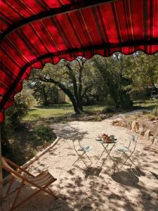 a table and chairs under a red roof at La Roulotte Authentique in Grignan