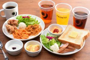 a table with two plates of food and two glasses of beer at Hakata Green Hotel Tenjin in Fukuoka
