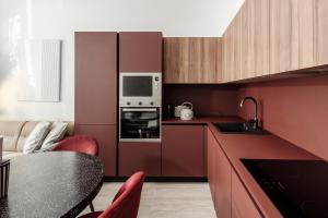 a kitchen with red cabinets and a table with a microwave at Ellul Living in Il-Furjana