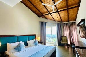 a bedroom with a large bed with a desk and a window at The Hills By First Team in Kandy