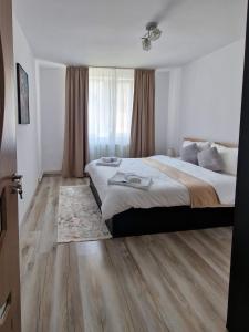 Un dormitorio con una cama grande y suelos de madera. en Relax Home, en Curtea de Argeş