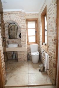 a bathroom with a white toilet and a brick wall at Oldies Hotel in Antalya +58 photos