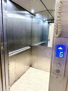 a elevator with a blue sign in a room at Ajman Friends Downtown Apartment Fully Yours Two Rooms and Kitchen for 3 People in Ajman 