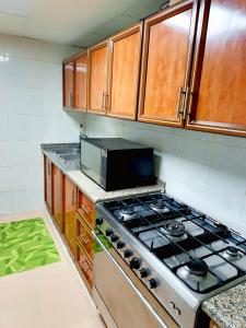 a kitchen with a stove and a microwave at Ajman Friends Downtown Apartment Fully Yours Two Rooms and Kitchen for 3 People in Ajman 
