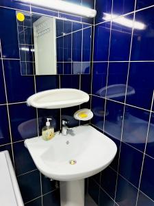 a blue tiled bathroom with a sink and a mirror at Ajman Friends Downtown Apartment Fully Yours Two Rooms and Kitchen for 3 People in Ajman  +13 photos