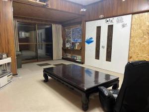 a living room with a table and a leather chair at ゲストハウス潮目 in Shibetsu