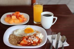 a table with two plates of breakfast food and a cup of coffee at Capital O Hotel Casa Blanca, Morelia in Morelia