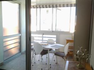 a dining room with a table and chairs and windows at De la Gardiole à la mer in Frontignan