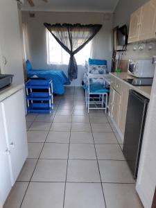 a kitchen with a white tiled floor and a window at Hope's Rest in Hibberdene