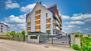 un edificio bianco con una recinzione di fronte a una strada di Apartament SPA 2 USTRONNIE Residence - 5D Apartments a Ustronie Morskie