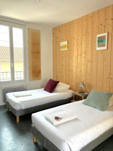 two beds in a room with wooden walls at LES BAIGNEURS in Saint-Gilles-Croix-de-Vie