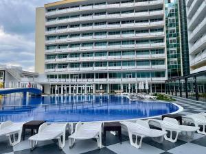 a large building with a large swimming pool with white chairs at Grand Hotel Nirvana - All Inclusive & Free Beach Access in Sunny Beach