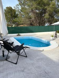 a chair and an umbrella next to a swimming pool at Chalet con piscina dogfriendly - alojamiento entero in Algar de Palancia