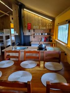 a kitchen with a wooden table with chairs and a sink at Beara Lodge Glamping in Beaworthy