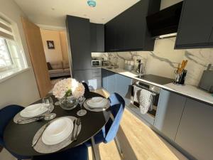 a kitchen with a black table and blue chairs at Luxury 4-Bedroom Haven Garden Parking in South Norwood