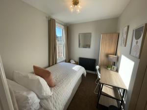 a small bedroom with a bed and a window at Luxury 4-Bedroom Haven Garden Parking in South Norwood