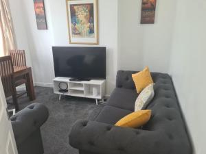 a living room with a couch and a tv at L & J ESCAPES-4 BEDROOMs SUITABLE FOR CONTRACTORS AND FAMILIES- LARGE PRIVATE PARKING-10 MINUTES TO M6 JUNCTION 9 in Coseley