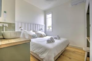 a bedroom with a large white bed and a sink at Le Banc de Sable - A 5 min de la plage in Arcachon