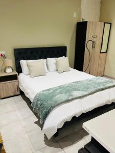 a bedroom with a large bed with a green blanket on it at The Corner Nest in Roodepoort