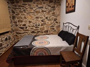 ein kleines Bett in einem Zimmer mit einer Steinmauer in der Unterkunft Casa Vacacional Familia Ferro in Cartelle