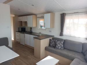 a living room with a couch and a kitchen at Camping Alkenhaer Appelscha Chalet 111 in Appelscha +8 photos