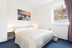 a bedroom with a white bed and a window at Haus Panorama Laboe Nr 1 in Laboe