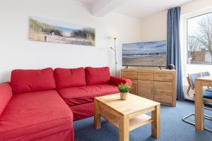 a living room with a red couch and a table at Haus Panorama Laboe Nr 1 in Laboe