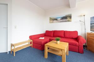 a living room with a red couch and a table at Haus Panorama Laboe Nr 1 in Laboe