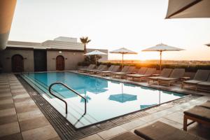 une piscine avec chaises et parasols sur un immeuble dans l'établissement Samluxurydesertcamp, à Sām