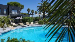 a large swimming pool with chairs and a building at Le Spinaker in Le Grau-du-Roi