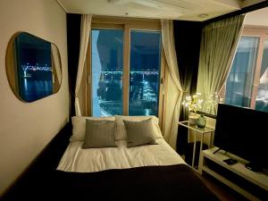 a bedroom with a bed with a window and a television at Ocean Front Apartment in Busan