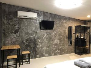 a bedroom with a black wall with a tv and two chairs at บ้านสวนวงศ์จินดารักษ์ in Phayao