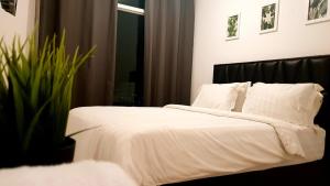 a bedroom with a bed with white sheets and a plant at Alpine Room at TreePark City Apartement in Tangerang