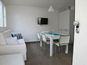 una sala da pranzo con tavolo, sedie e divano di COSTA FENICIA RESIDENCE - Aura Club a Scoglitti
