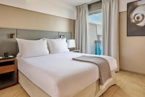 a large bed in a hotel room with a window at Fraser Suites Paris La Défense in Courbevoie +87 photos