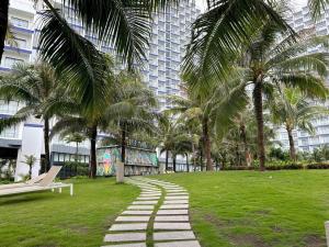 a park with a bench and palm trees in front of a building at Arena jakovi condotel in Cam Ranh International Airport